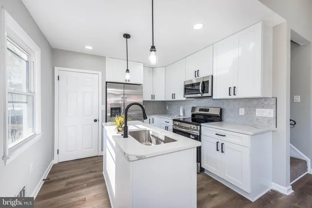 a kitchen with stainless steel appliances granite countertop a stove a sink dishwasher a refrigerator and a microwave oven with wooden floor