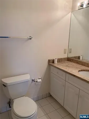 a bathroom with a granite countertop toilet and a sink
