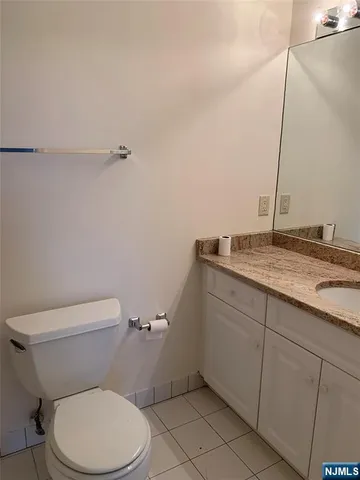 a bathroom with a granite countertop toilet and a sink