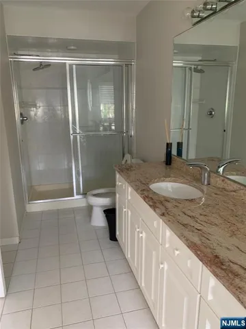 a bathroom with a granite countertop sink a toilet and a shower