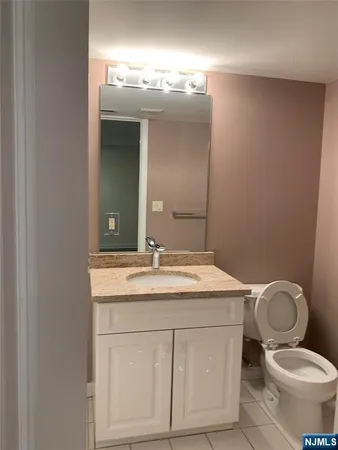 a bathroom with a granite countertop toilet sink and mirror