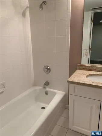 a bathroom with a granite countertop sink and a bathtub