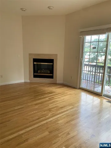 a view of an empty room with glass door and wooden floor
