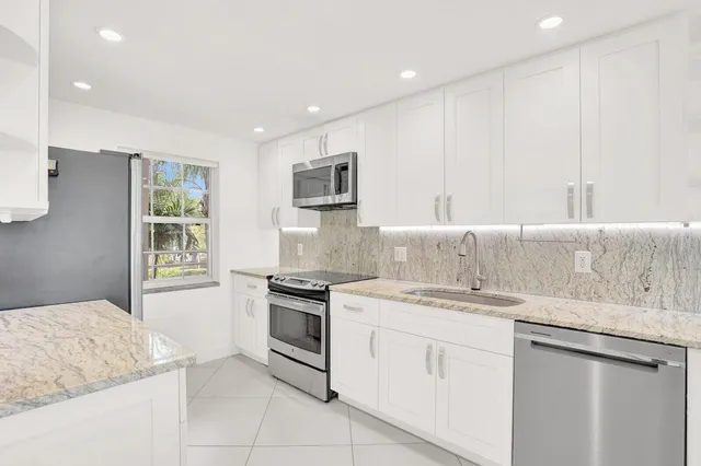 a kitchen with granite countertop white cabinets and white appliances