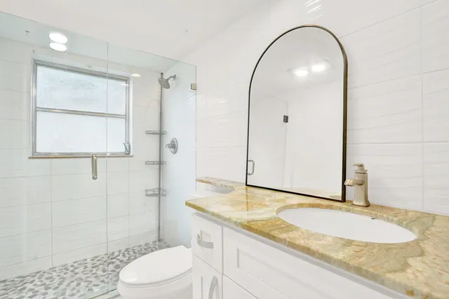 a bathroom with a granite countertop sink toilet and shower