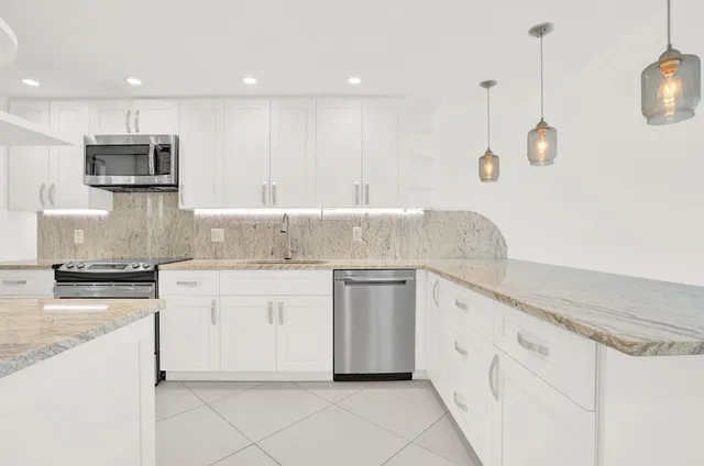 a kitchen with granite countertop white cabinets white stainless steel appliances with a sink and dishwasher