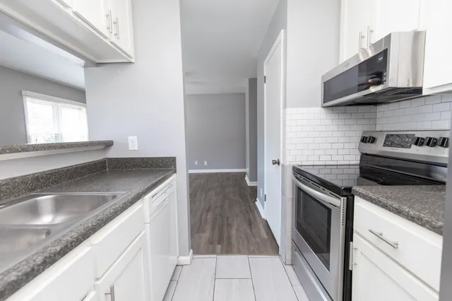 a kitchen with granite countertop a sink dishwasher stove and oven with wooden floor