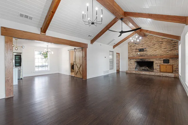 a view of an empty room with wooden floor fireplace and a window