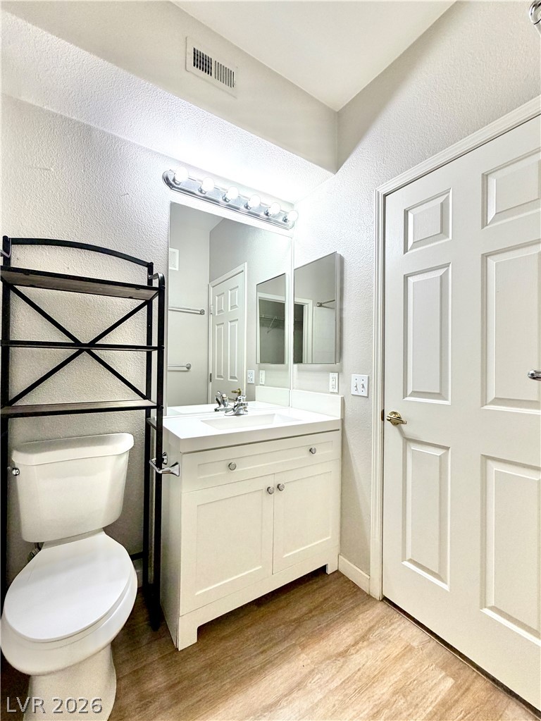 8555 West Russell Road, Unit 2018 Las Vegas, NV 89113 - Photo 17 of 23 A compact bathroom offers functionality with a vanity, toilet, and durable wood-look flooring.