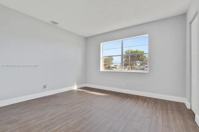 an empty room with wooden floor & windows
