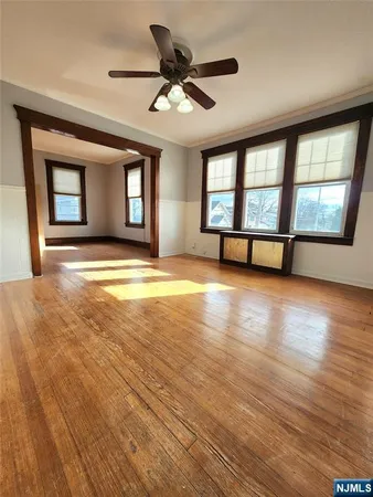 a view of an empty room with window and wooden floor