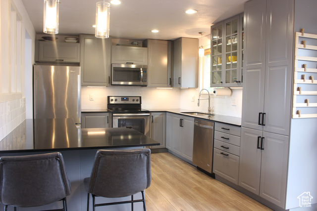 4066 West Juniper Road Cedar Hills, UT 84062 - Photo 1 of 1 Kitchen with appliances with stainless steel finishes, decorative light fixtures, sink, a breakfast bar area, and gray cabinetry