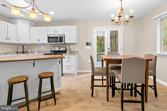 a kitchen with stainless steel appliances granite countertop a white table chairs and a refrigerator