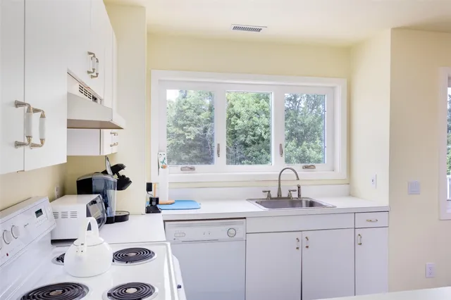 a kitchen with sink a large window cabinets and a couch