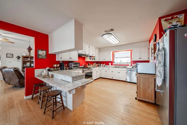 a kitchen with stainless steel appliances granite countertop a sink cabinets and wooden floor