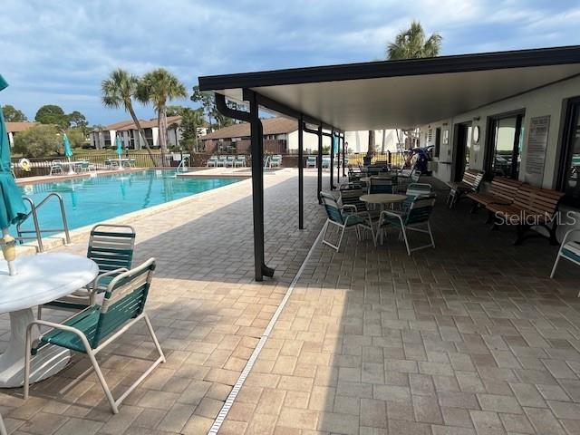 1725 Pine Ridge Way East, Unit C Palm Harbor, FL 34684 - Photo 25 of 28 a view of a patio with dining table and chairs with a garden