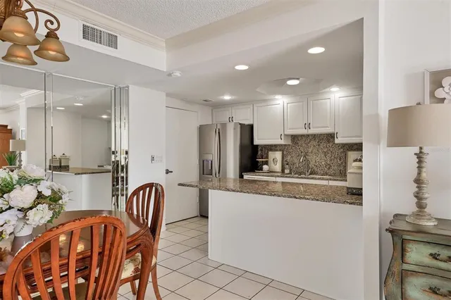 a kitchen with stainless steel appliances granite countertop a refrigerator a stove a sink a dining table and chairs with wooden floor