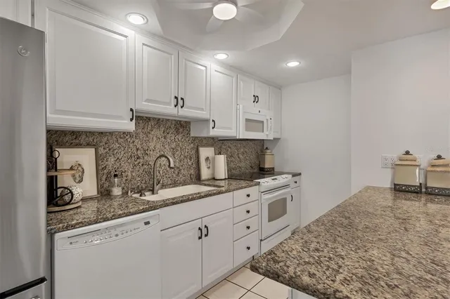 a kitchen with granite countertop a sink a stove and cabinets