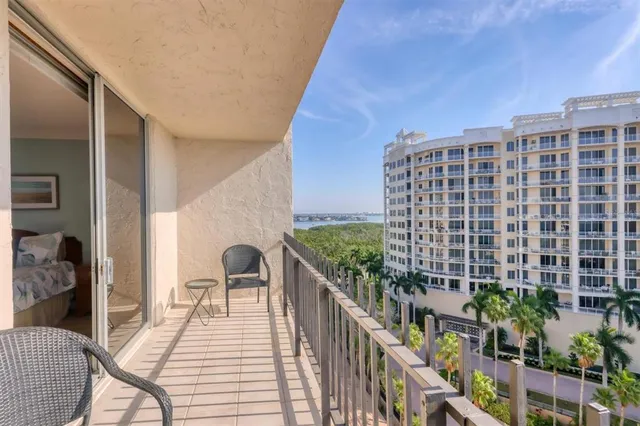 a balcony with table and chairs and potted plants