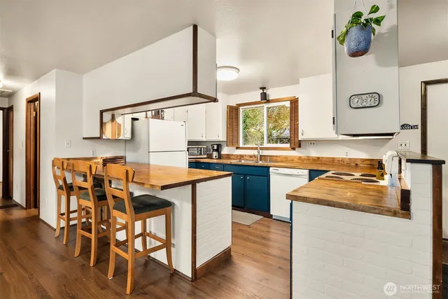 a kitchen with granite countertop a table chairs stove and wooden floor