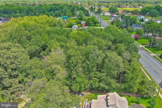 an aerial view of residential house with outdoor space and trees all around