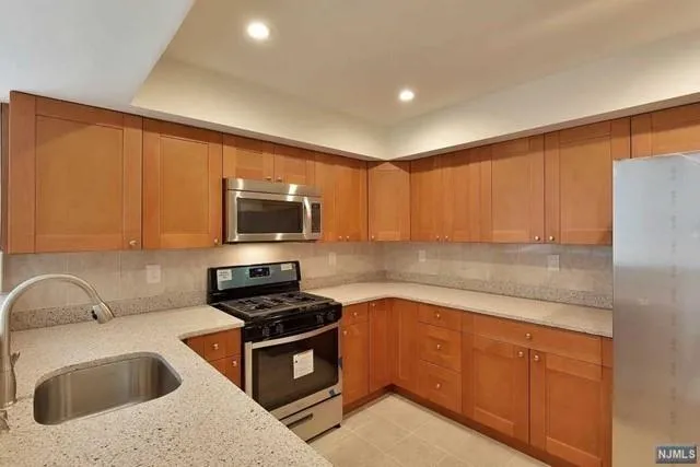 a kitchen with granite countertop a sink stainless steel appliances and cabinets