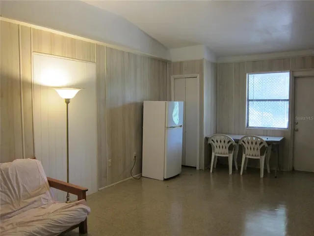 a living room with furniture a dining table and a refrigerator