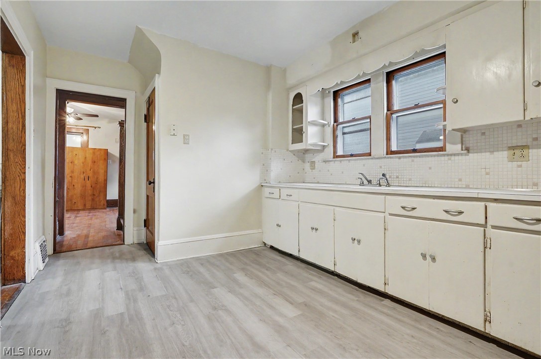 456 Delmar Avenue Akron, OH 44310 - Photo 9 of 27 Kitchen featuring light wood-finish flooring, white cabinetry, white countertops, a tiled backsplash, and dual windows