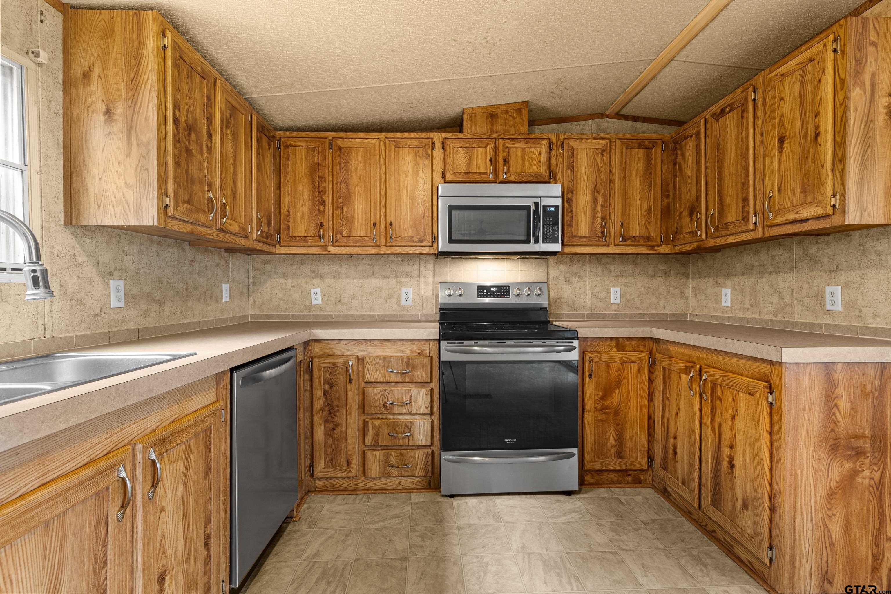 200 County Road 2123 Longview, TX 75603 - Photo 9 of 22 a kitchen with stainless steel appliances granite countertop a stove a sink dishwasher and a microwave oven on the wall