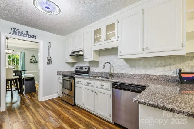 a kitchen with stainless steel appliances granite countertop a sink stove and cabinets