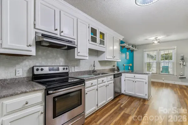 a kitchen with stainless steel appliances granite countertop a stove and white cabinets