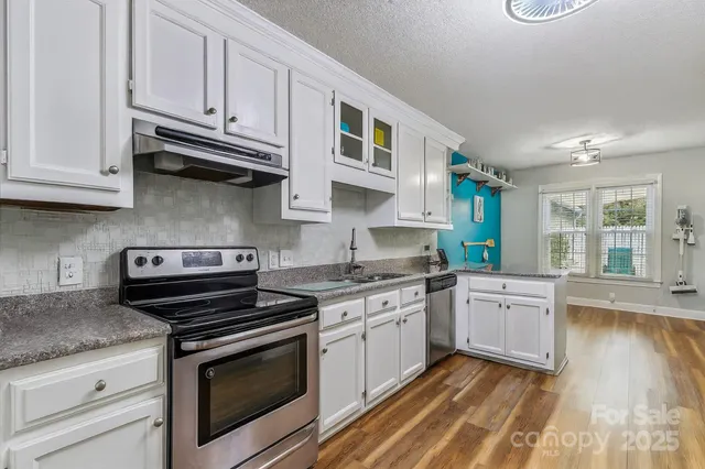 a kitchen with stainless steel appliances granite countertop a stove and white cabinets