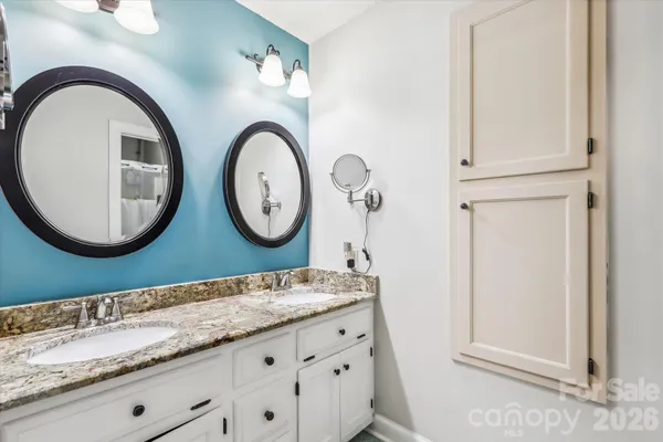a bathroom with a granite countertop double vanity sink and mirror