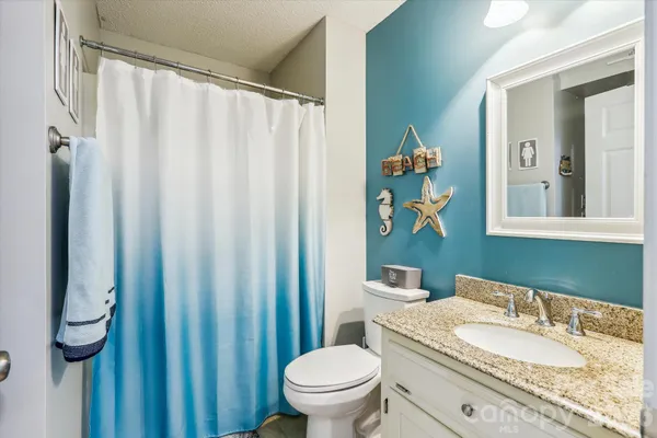 a bathroom with a granite countertop sink and a mirror with toilet
