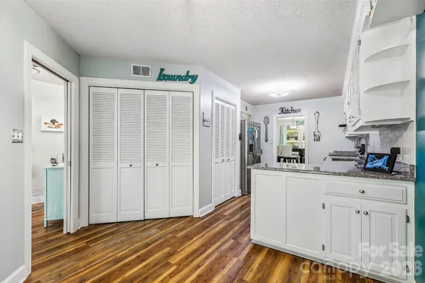 a kitchen with white cabinets and wooden floor