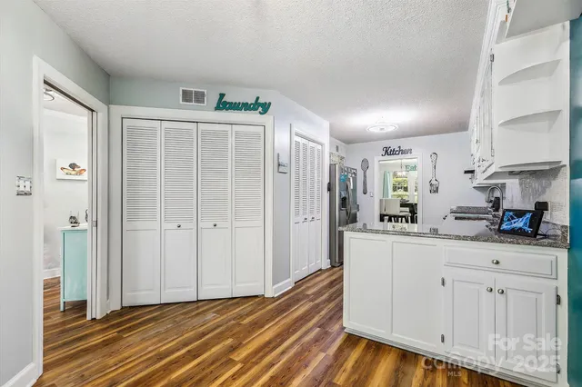 a kitchen with white cabinets and wooden floor