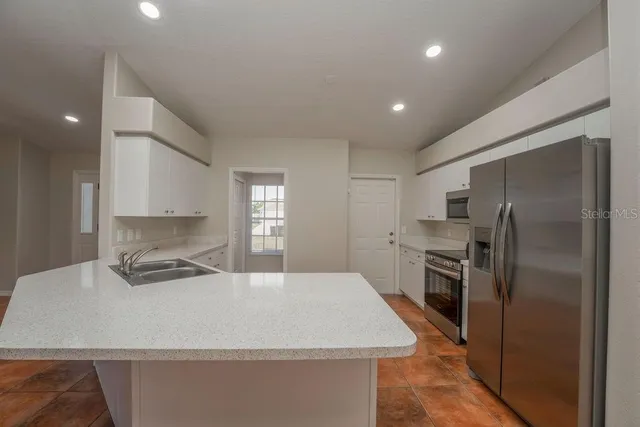 a kitchen with kitchen island a counter top space cabinets stainless steel appliances and a window
