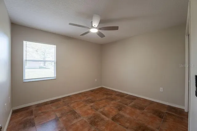 an empty room with windows and fan