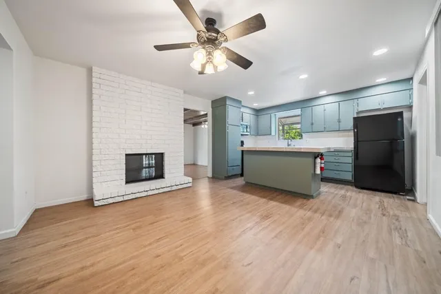 a living room with stainless steel appliances kitchen island a fireplace and wooden floor