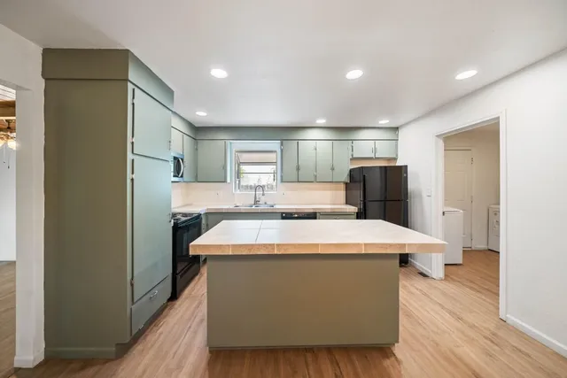 a kitchen with stainless steel appliances a refrigerator sink and wooden floor