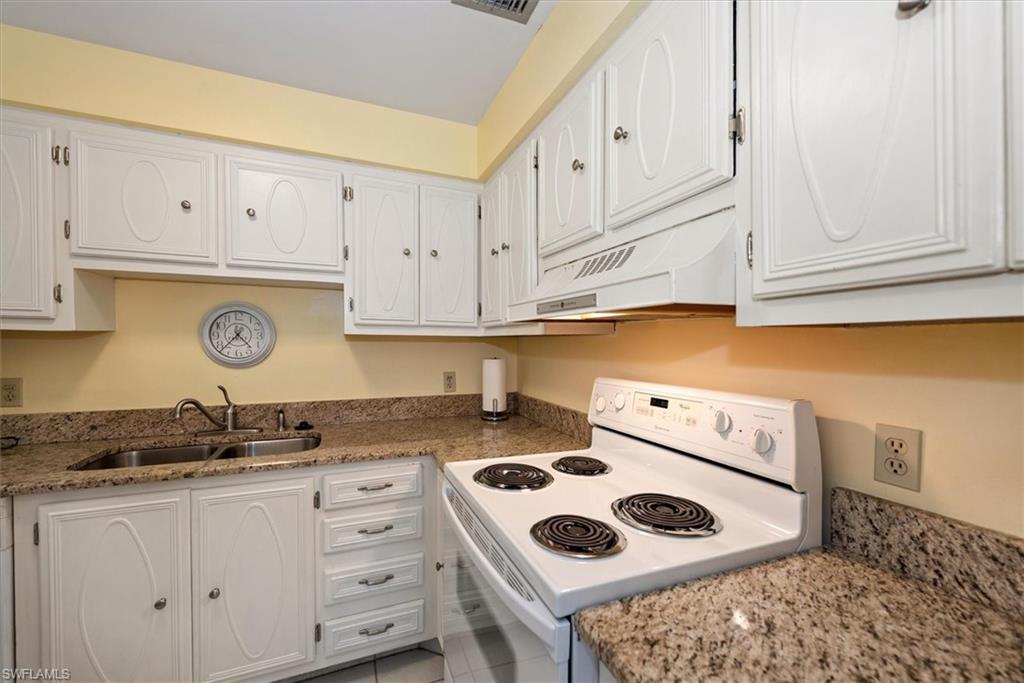 582 Broad Avenue South, Unit 582 Naples, FL 34102 - Photo 8 of 36 a kitchen with white cabinets and appliances