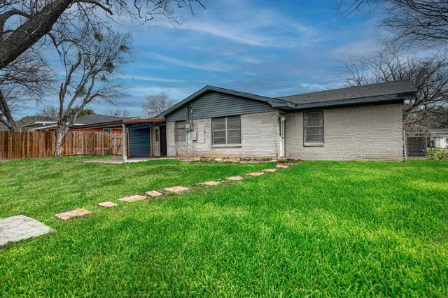 a brick house with a big yard plants and large trees