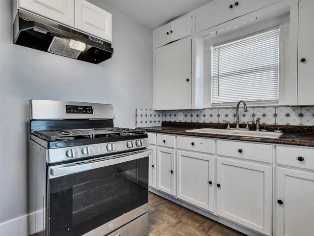 a kitchen with stainless steel appliances granite countertop white cabinets and a stove top oven