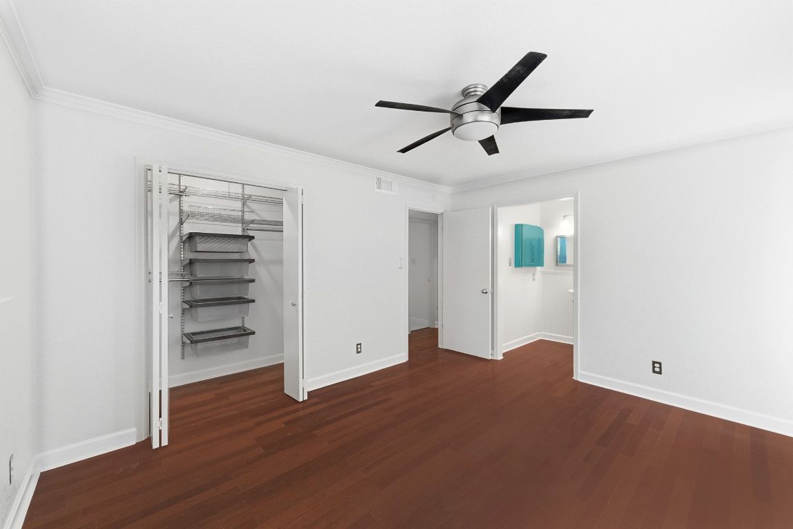 6210 Shadow Valley Drive, Unit B Austin, TX 78731 - Photo 18 of 28 Primary bedroom featuring dark wood finished floors, a closet, a ceiling fan, and ornamental molding