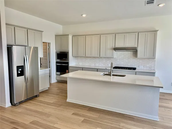a kitchen with stainless steel appliances a refrigerator and a stove top oven