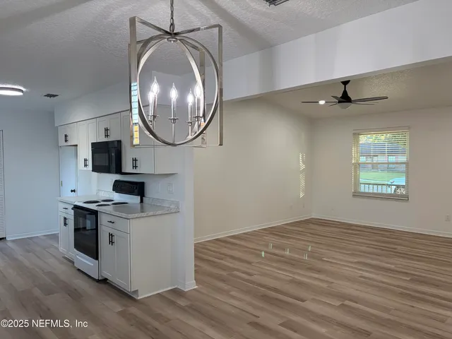 an empty room with wooden floor mirror and windows