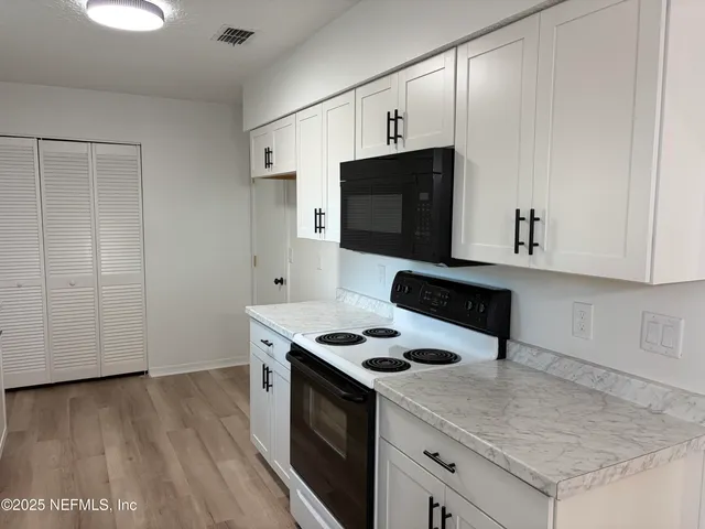 a kitchen with granite countertop a stove and a wooden floor
