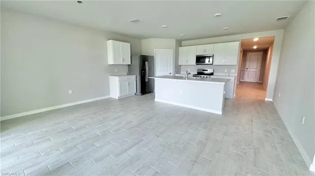 a view of kitchen with stainless steel appliances refrigerator stove microwave and cabinets