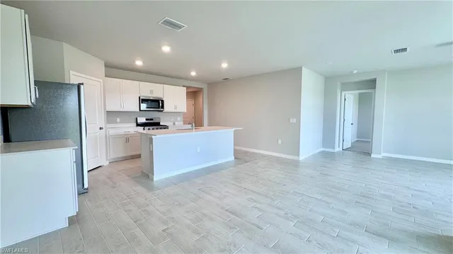 a view of kitchen with kitchen island a sink stainless steel appliances and cabinets