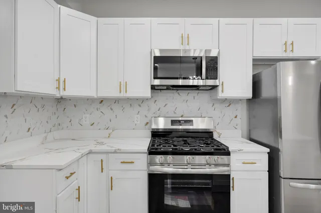 a kitchen with stainless steel appliances granite countertop white cabinets a stove a sink and dishwasher